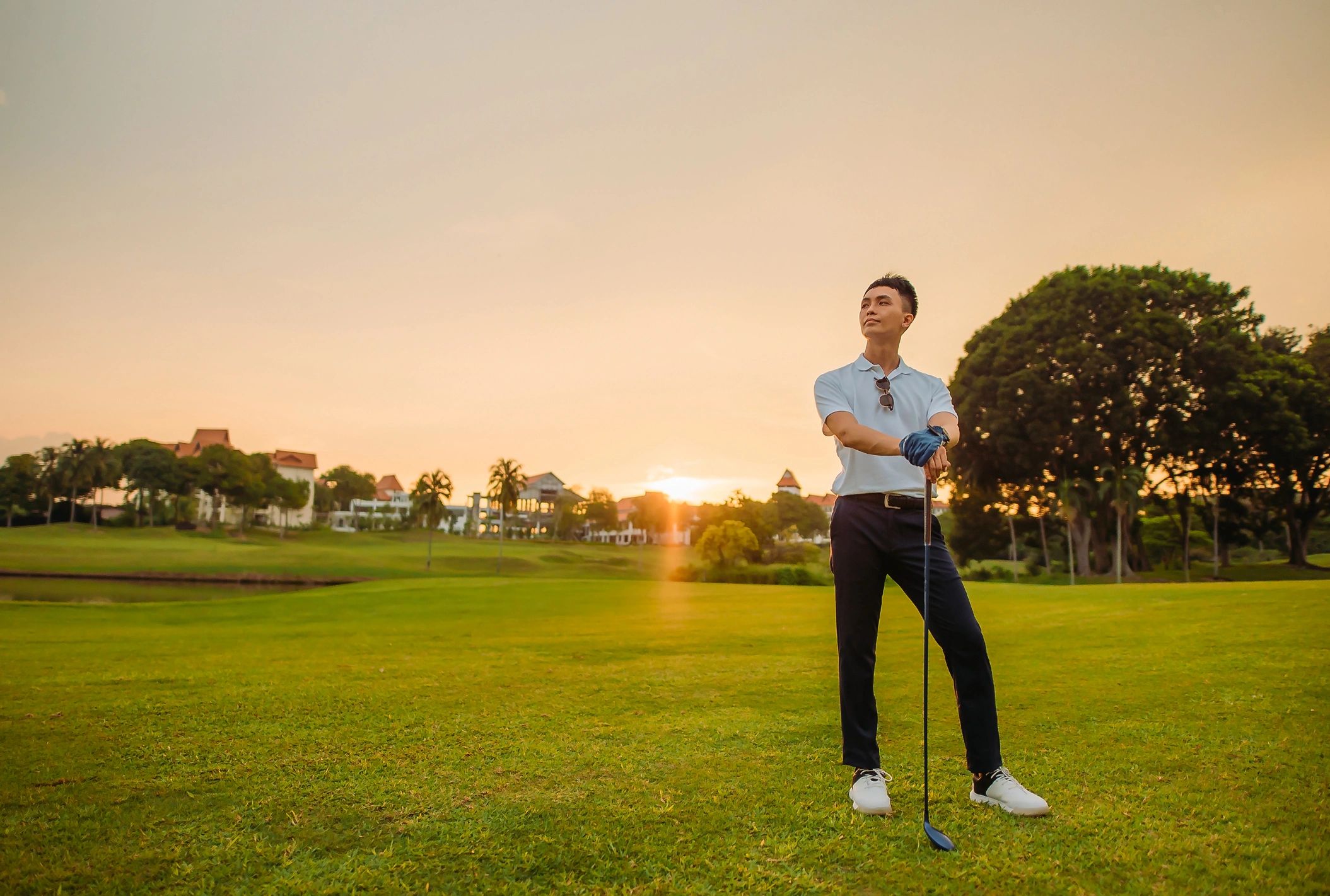 Male golfer holding a golf club at sunset