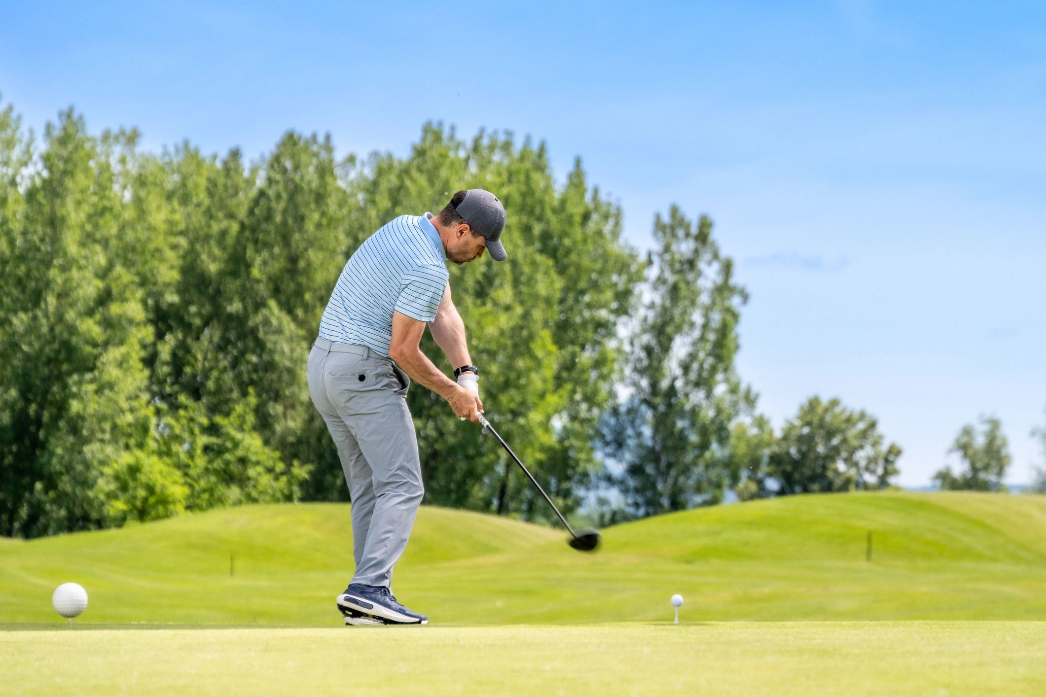 Golfer gripping a club during a swing on a sunny course